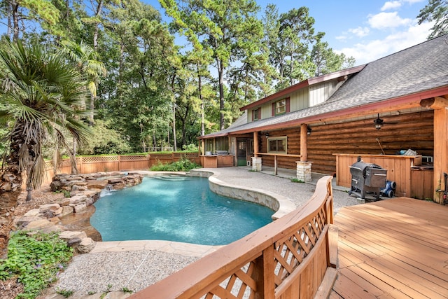 view of swimming pool featuring pool water feature, a grill, and a deck