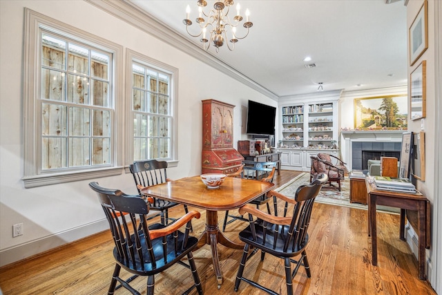 2509 Westgate Dr, Houston, TX 77019 - dining space with crown molding, a tile fireplace, a chandelier, wood finished floors, and built in features