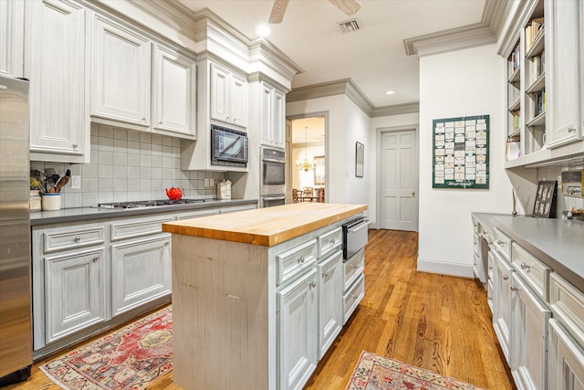 2509 Westgate Dr, Houston, TX 77019 - kitchen with butcher block countertops, ornamental molding, stainless steel appliances, decorative backsplash, and light wood finished floors