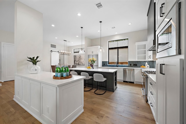 kitchen with a kitchen island, stainless steel appliances, light hardwood / wood-style flooring, and white cabinetry