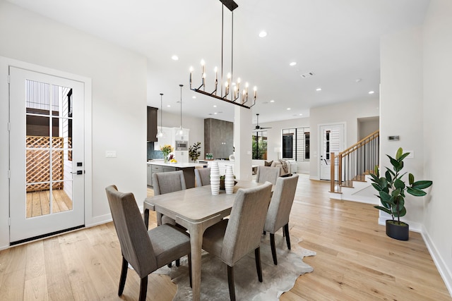 dining room with ceiling fan with notable chandelier and light hardwood / wood-style floors