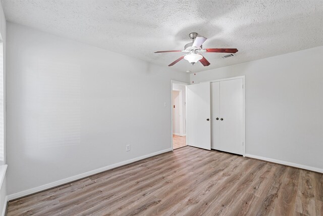 empty room with a textured ceiling, light hardwood / wood-style flooring, and ceiling fan