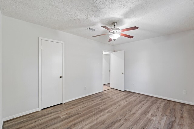 spare room featuring light wood-type flooring, ceiling fan, and a textured ceiling