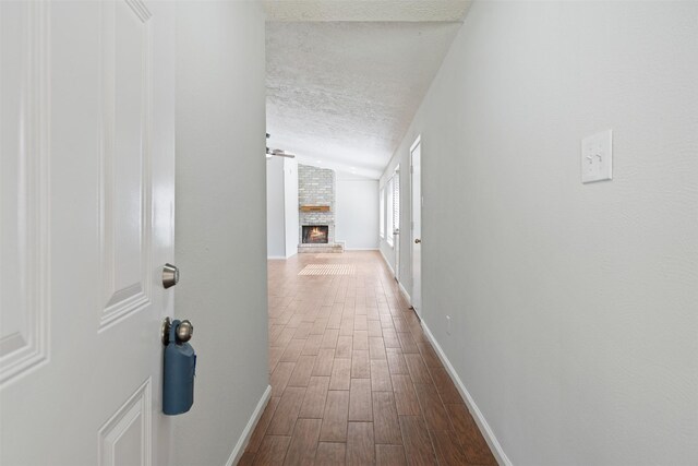 hall with vaulted ceiling, a textured ceiling, and wood-type flooring