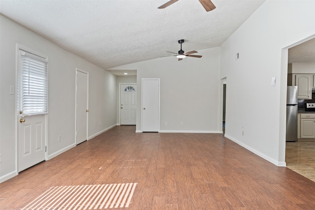 spare room with a textured ceiling, ceiling fan, vaulted ceiling, and light hardwood / wood-style floors