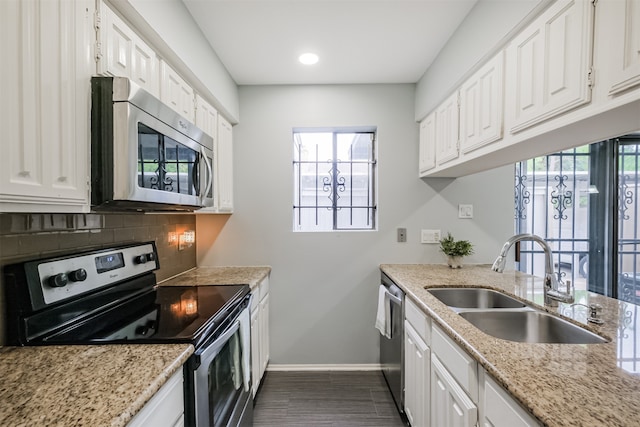 kitchen with appliances with stainless steel finishes, decorative backsplash, light stone countertops, white cabinets, and sink