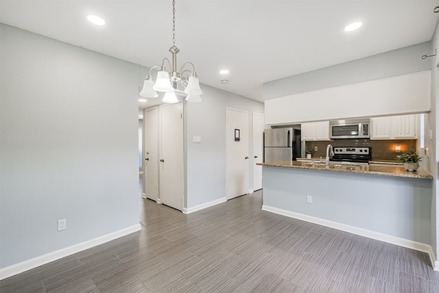 kitchen featuring a notable chandelier, kitchen peninsula, white cabinetry, hanging light fixtures, and appliances with stainless steel finishes