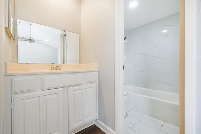 full bathroom with ceiling fan, tiled shower / bath combo, vanity, and toilet