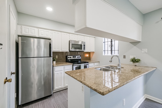 kitchen with kitchen peninsula, appliances with stainless steel finishes, sink, and white cabinetry