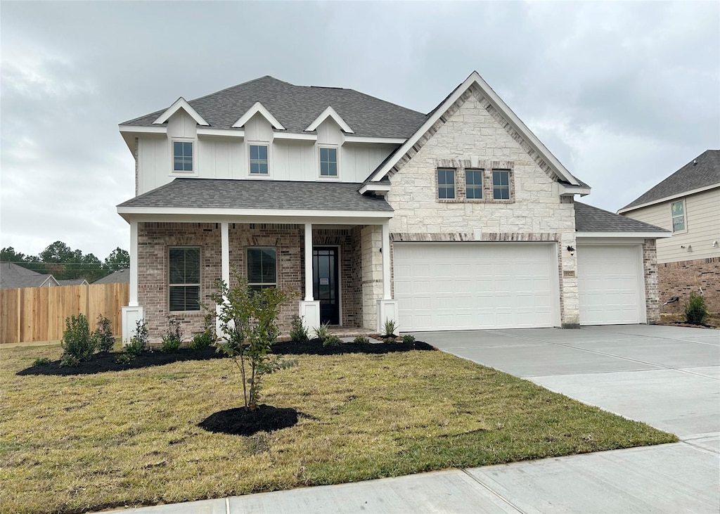 view of front of home with a porch, a front yard, and a garage