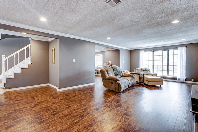 living room with crown molding, wood finished floors, visible vents, and baseboards