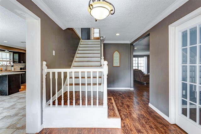 stairs with a textured ceiling, hardwood / wood-style flooring, and sink