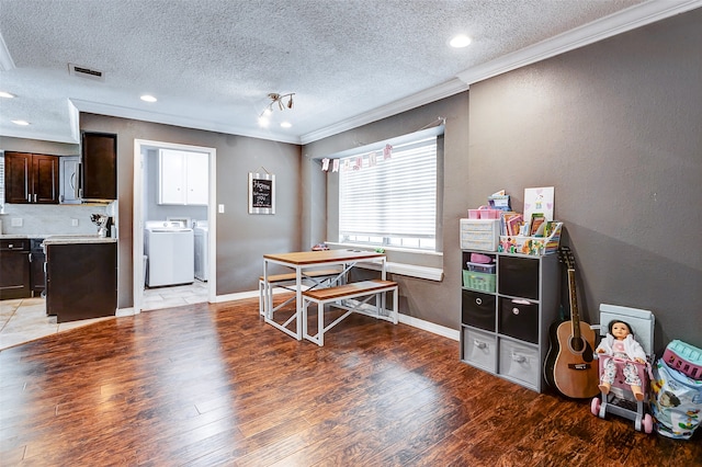 dining room with hardwood / wood-style floors, washing machine and dryer, a textured ceiling, and ornamental molding