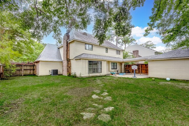 rear view of property with cooling unit, a lawn, and a patio area