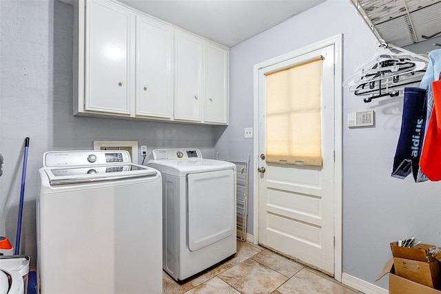 clothes washing area featuring cabinets and washer and clothes dryer