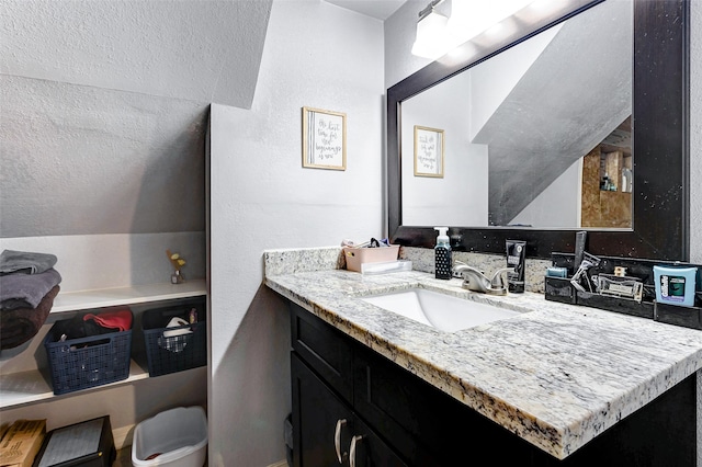 bathroom featuring a textured ceiling, vanity, and lofted ceiling