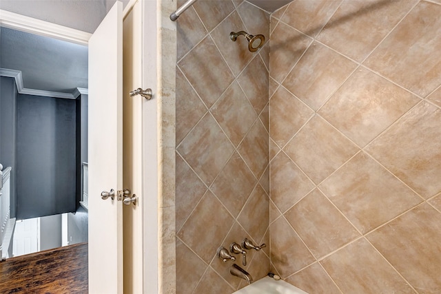 bathroom with crown molding and tiled shower / bath combo