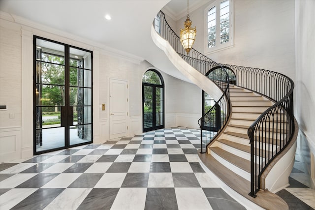 foyer with ornamental molding, a chandelier, and french doors