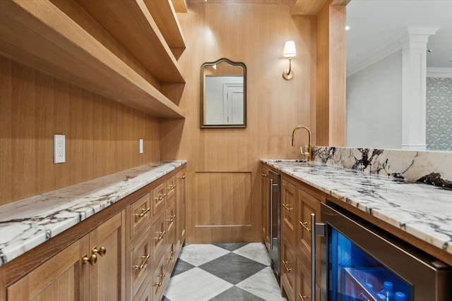 bar with ornamental molding, beverage cooler, light stone counters, and sink