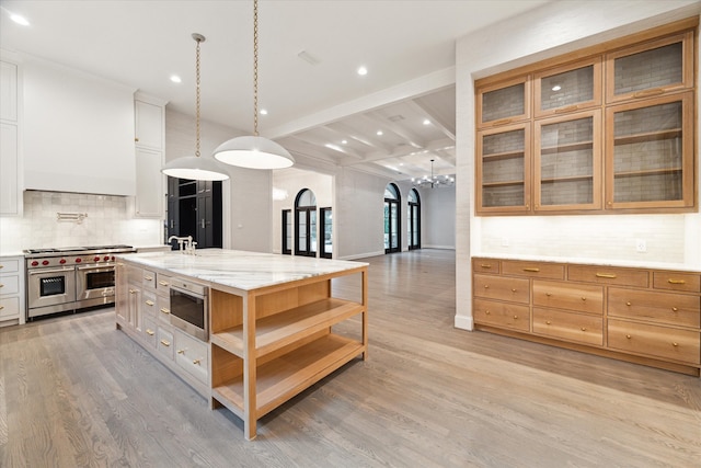 kitchen with light wood-type flooring, white cabinetry, stainless steel appliances, and a center island with sink