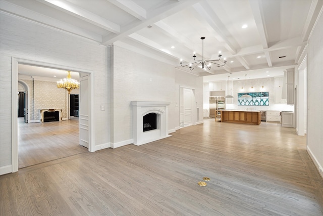 unfurnished living room featuring a notable chandelier, beam ceiling, and light hardwood / wood-style floors