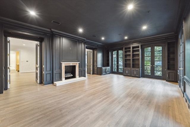 unfurnished living room featuring ornamental molding, french doors, built in features, and light hardwood / wood-style floors