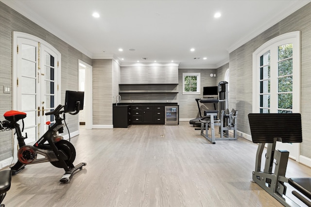 workout room with light hardwood / wood-style flooring, ornamental molding, and french doors