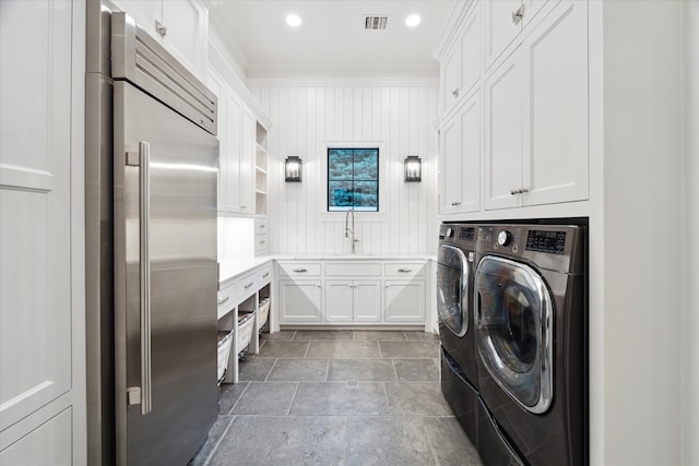 laundry area with ornamental molding, cabinets, washer and dryer, and sink