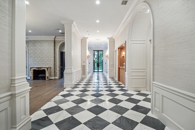 hallway with light hardwood / wood-style flooring, ornate columns, and ornamental molding