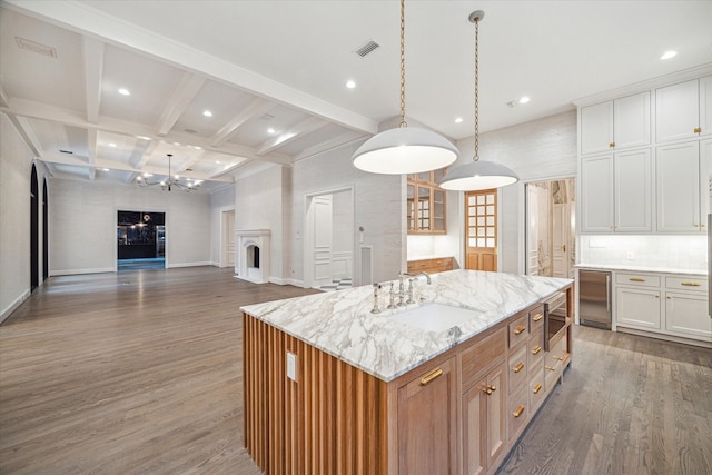 kitchen with a kitchen island with sink, white cabinetry, dark hardwood / wood-style flooring, sink, and stainless steel microwave