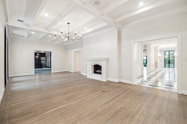 unfurnished living room featuring hardwood / wood-style flooring, a chandelier, and beam ceiling