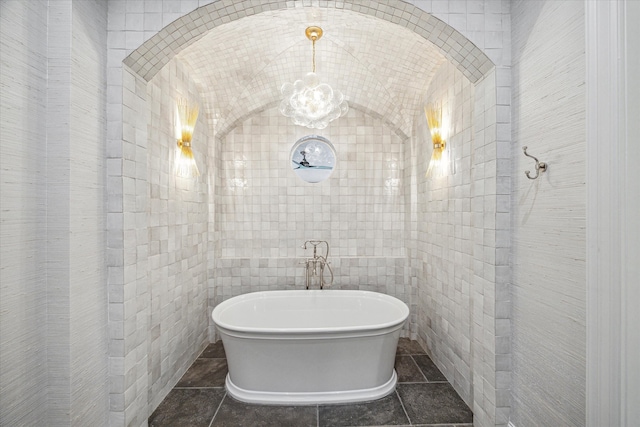 bathroom featuring tile patterned flooring, tile walls, and a washtub