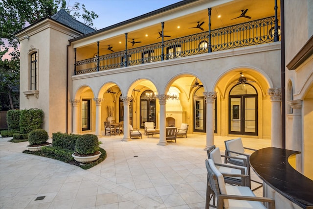 back house at dusk featuring a balcony, outdoor lounge area, and a patio