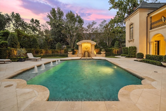 pool at dusk featuring a patio