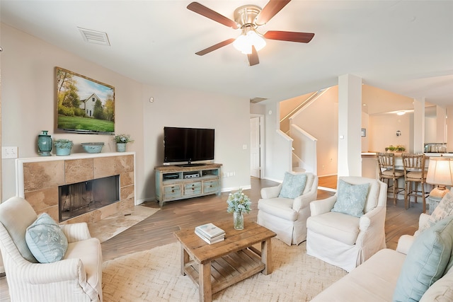 living room featuring a fireplace, wood-type flooring, and ceiling fan