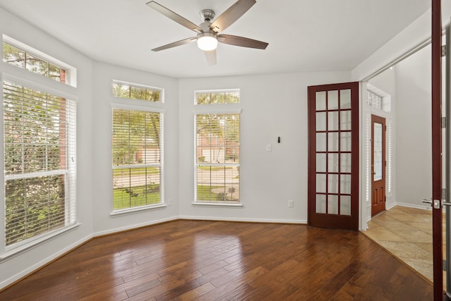 empty room featuring dark wood-type flooring, ceiling fan, and a healthy amount of sunlight