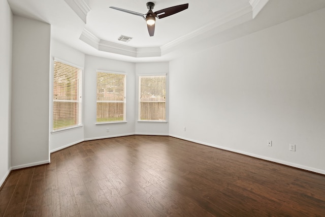 empty room with a raised ceiling, ceiling fan, ornamental molding, and dark hardwood / wood-style floors