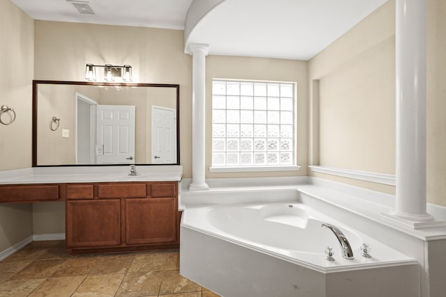 bathroom with decorative columns, vanity, and a tub to relax in