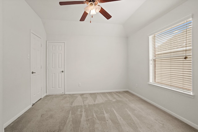 spare room with ceiling fan, light carpet, and vaulted ceiling