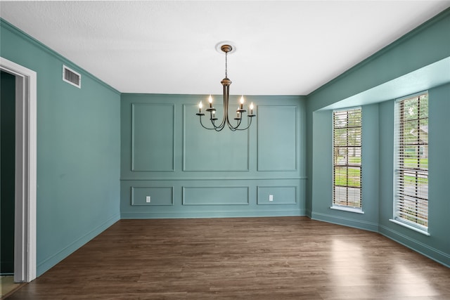 unfurnished dining area with ornamental molding, a notable chandelier, and dark hardwood / wood-style floors