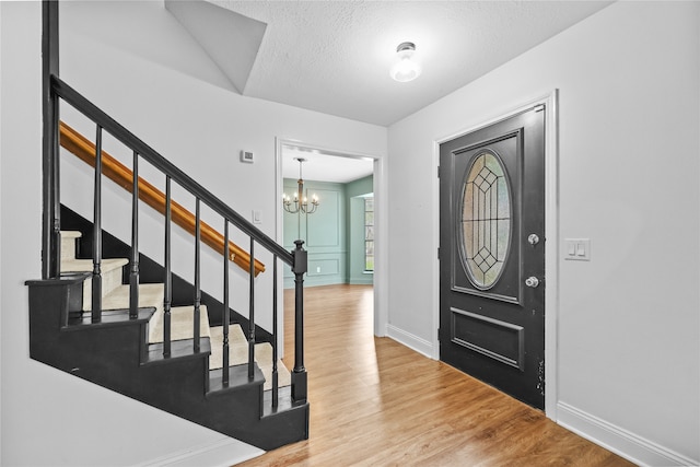 foyer featuring hardwood / wood-style flooring, a chandelier, and a textured ceiling