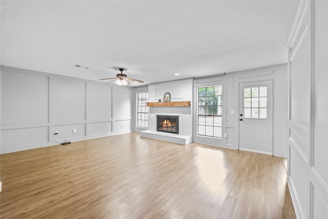 unfurnished living room featuring a brick fireplace, ceiling fan, and light hardwood / wood-style floors