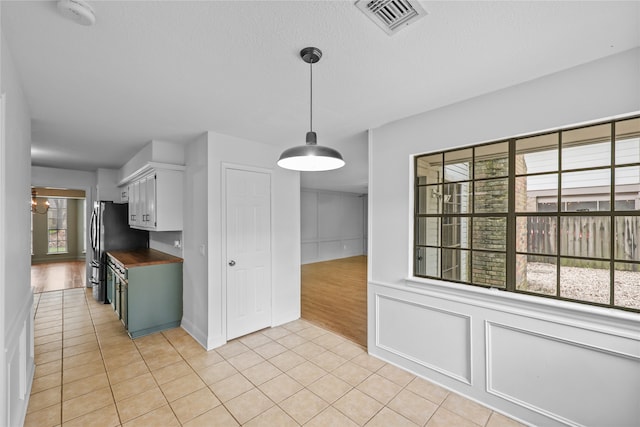 kitchen featuring light hardwood / wood-style flooring, butcher block counters, white cabinets, and hanging light fixtures