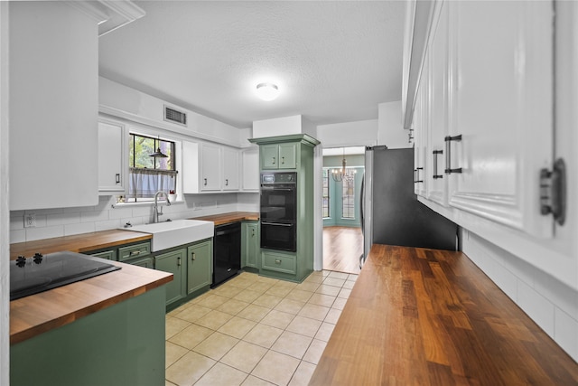 kitchen with light hardwood / wood-style flooring, green cabinetry, wooden counters, black appliances, and sink