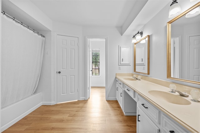 bathroom featuring wood-type flooring, shower / bath combo with shower curtain, and vanity