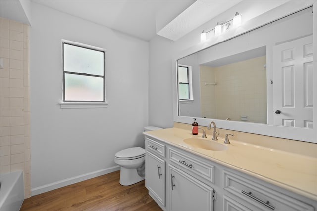 full bathroom featuring vanity, hardwood / wood-style floors, toilet, a skylight, and tiled shower / bath combo