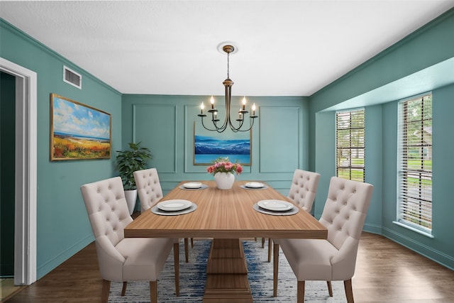 dining space with crown molding, dark wood-type flooring, and an inviting chandelier