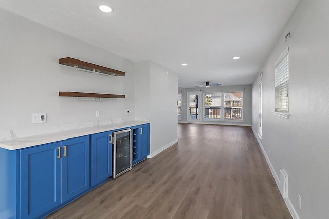 bar featuring light stone countertops, ceiling fan, blue cabinetry, dark hardwood / wood-style floors, and wine cooler