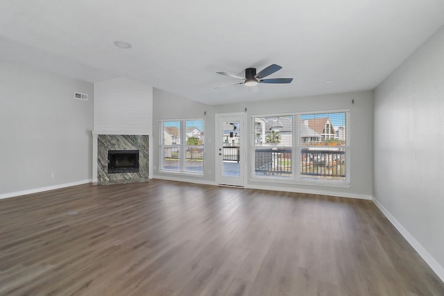 unfurnished living room featuring ceiling fan, dark hardwood / wood-style flooring, a premium fireplace, and a wealth of natural light