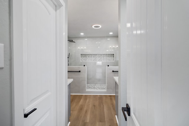 bathroom featuring vanity, wood-type flooring, and tiled shower